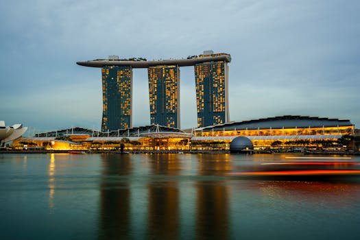 Marina Bay Sands illuminated at sunset in Singapore, reflecting on calm waters.