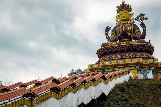 Giant Buddha statue at Pelling Monastery, Sikkim, under a cloudy sky, showcasing spiritual and cultural heritage.