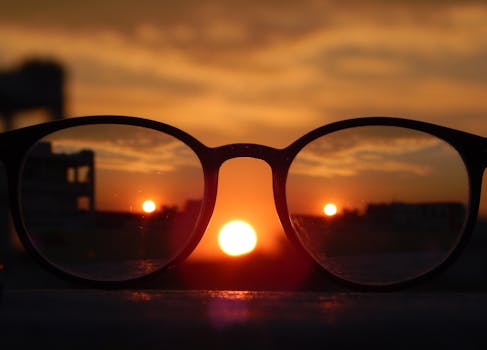 Blurred sunset view mirrored through eyeglasses, capturing a unique perspective on a serene landscape.